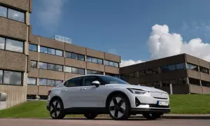 Vit Polestar 2 parkerad framför ett modernistiskt betonghus. Bilen är redo för en polestar 2 testkörning i solsken.
