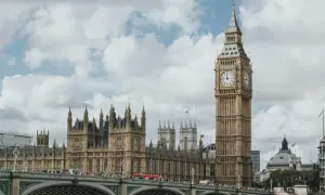 Big Ben i Parlament w Londynie, stolicy UK, na tle chmur. Most pełen ludzi i czerwony autobus.