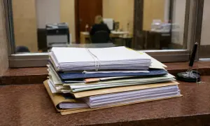 Stos dokumentów do sprawy spadkowej w sądzie, gotowy do złożenia. Obok długopis na łańcuszku.