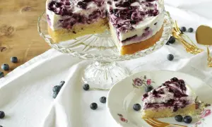 Ein köstliches Heidelbeertorte Rezept: saftiger Boden, cremige Füllung und frische Heidelbeeren. Ein Stück auf einem Teller mit goldenem Besteck.