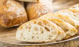 Frisch gebackene Ciabatta-Brote, aufgeschnitten auf einem Holzbrett. Das luftige Innere und die knusprige Kruste zeigen das gelungene Ciabatta Rezept.