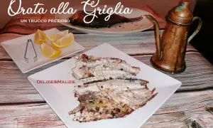 Orata alla griglia succulenta, servita con spicchi di limone e un'antica oliera in rame. Un vero tesoro culinario.