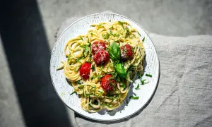 Spaghetti mit cremigem Pesto Trapanese, garniert mit Kirschtomaten und Basilikum.