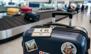 Bagaż rejestrowany kosztuje 50 euro. Na walizce widać etykietę z tą informacją i naklejki z podróży.