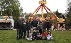 Famiglie giostrai italiani posano sorridenti davanti a un'attrazione "Extreme" in un parco divertimenti.