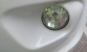 Zbliżenie na reflektor przeciwmgielny w białym zderzaku. Dowiedz się, jak włączyć światła przeciwmgielne, by poprawić widoczność.