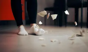 Fragmenty talerza wirują w powietrzu, gdy stopy w skarpetkach stoją na podłodze. Czy to skutek nieuwagi, czy może zaniki pamięci?