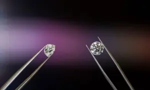 Dwa kamienie szlachetne w pęsecie: surowy brylant i oszlifowany diament.