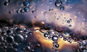 Close-up of oil and water bubbles with iridescent colors and reflections.