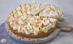 Une magnifique tarte au citron meringuée, parfaite pour une recette facile. Les pointes de meringue dorées et les petites fleurs blanches ajoutent une touche gourmande.