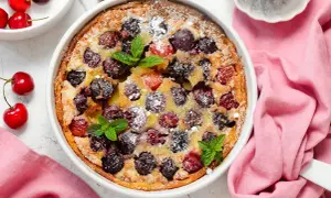 Clafoutis aux cerises, une recette de Laurent Mariotte, parsemé de sucre glace et décoré de feuilles de menthe.