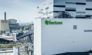 Nowoczesna elektrociepłownia Fortum z zielonym logo, w tle kominy i chłodnia kominowa.