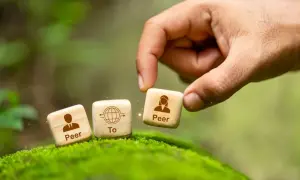 Dłoń układa kostki symbolizujące p2p: "Peer To Peer".