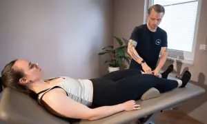 Mann führt Lymphdrainage Massage am Bein einer liegenden Frau durch.