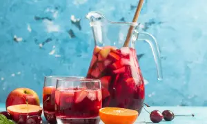 En karaff med röd bål fylld med frukt och is, serverad med två glas och färsk frukt. Perfekt för ett somrigt bål recept.