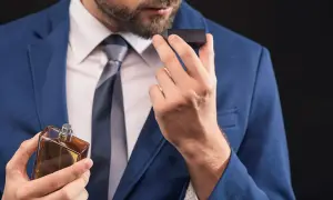 Elegancki mężczyzna w garniturze wącha perfumy. Czy to woda toaletowa czy perfumowana?