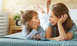 Mutter und Kind liegen auf dem Bett und sprechen. Das Kind übt emotionsregulation kinder, während die Mutter liebevoll zuhört.