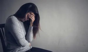 Kobieta z ręką na twarzy, pogrążona w smutku. Jak pomóc osobie z depresją która nie chce pomocy? Cierpliwość i wsparcie są kluczowe.