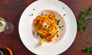 Pasta mit Lachs in cremiger Sauce, garniert mit Petersilie und Zitrone.