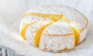 Ser camembert w ciąży, z widocznymi kawałkami, prezentuje swoje kremowe wnętrze.