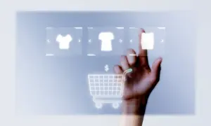 Mano tocando pantalla virtual con iconos de camisetas y carrito de compra. Guía para saber como abrir una tienda online en España.