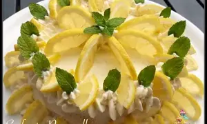 Delizia al limone, una torta fresca e profumata, decorata con fette di limone e foglie di menta.