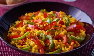 Un plat appétissant de riz à l'espagnol, garni de poivrons rouges et verts, et de chorizo.