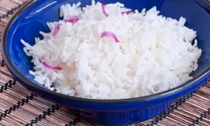 Aksamitny ryż basmati ig w niebieskiej miseczce, ozdobiony delikatnymi płatkami kwiatów.