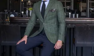 Elegancki mężczyzna w zielonej marynarce w kratę i granatowych spodniach. Idealne połączenie, jeśli zastanawiasz się, jakie spodnie do zielonej koszuli.