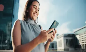 Uśmiechnięta kobieta sprawdza na telefonie, jak sprawdzić ile zostało internetu.