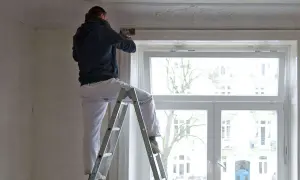 Mann auf Leiter renoviert Wohnung. Mieterrechte bei Sanierung beachten.