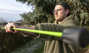 Mann mit Brille und Kappe trainiert mit einem leuchtend grünen Schwingstab, bereit für den Decathlon.
