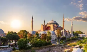 Majestatyczny meczet Hagia Sophia w Stambule, z minaretami i kopułami, oświetlony zachodzącym słońcem.