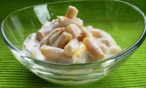 Gelber Bohnensalat in einer Glasschüssel auf grünem Hintergrund.