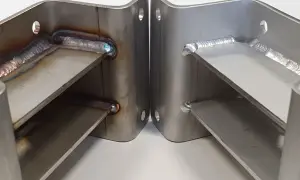 Dwa metalowe wsporniki ze stali nierdzewnej, połączone spawami. Widoczne ślady po wytrawianiu stali nierdzewnej.