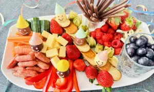 Bunter Snack-Teller mit Früchten, Käse, Würstchen und lustigen Figuren mit Partyhüten – perfekt für Fasching im Kindergarten!