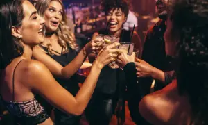 Glada vänner skålar i drinkar, en riktig Zakynthos fest-stämning på en livlig bar.