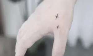 Dwa małe tatuaże męskie na rękę w kształcie gwiazdek.