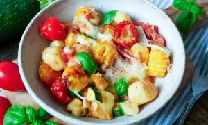 Herzhaftes Gnocchi Auflauf Rezept mit Tomaten, Zucchini und geschmolzenem Käse, garniert mit frischem Basilikum.