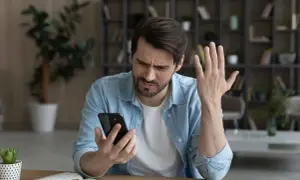 Mężczyzna zmartwiony przegrzewaniem się telefonu. Dba o bezpieczną temperaturę urządzenia, by uniknąć uszkodzeń.