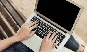 Dłonie na klawiaturze laptopa. Dowiedz się, jak zrobić screena na laptopie, by uwiecznić ważne momenty.