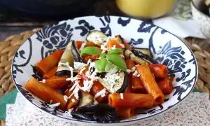 En skål med pasta alla norma med aubergine, tomatsås och basilika, toppad med riven ost.