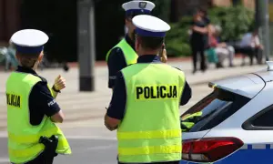 Policjanci w kamizelkach odblaskowych stoją obok radiowozu. Czy policja może wejść na teren prywatny bez nakazu?