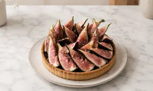 Tarte aux figues fraîchement préparée, garnie de quartiers de figues rouges et d'une touche de noix concassées. Un délice visuel et gustatif.
