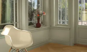 En ljus hall med en vit stol och en vas med blommor på fönsterbrädan. Väggarna är målade i en lugn grön nyans, vilket ger en harmonisk känsla.