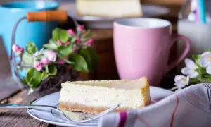 Pyszny sernik na talerzyku, obok różowy kubek. Zastanawiasz się, ile może stać sernik w lodówce?