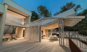 Terraza moderna con suelo de madera Accoya, pérgola y fachada acristalada.