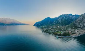 Panoramica del Lago di Garda con montagne imponenti e una città pittoresca. Perfetto per scoprire le **Unternehmungen Gardasee**.