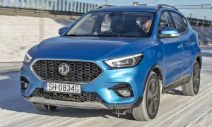 Niebieski MG ZS Classic jedzie po zaśnieżonej drodze. Kierowca w okularach prowadzi auto.