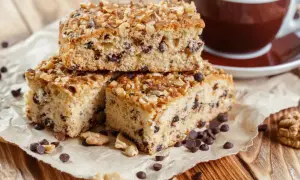 Fette di ciambellone marchigiano ricetta originale, con gocce di cioccolato e noci, accanto a una tazza di caffè.